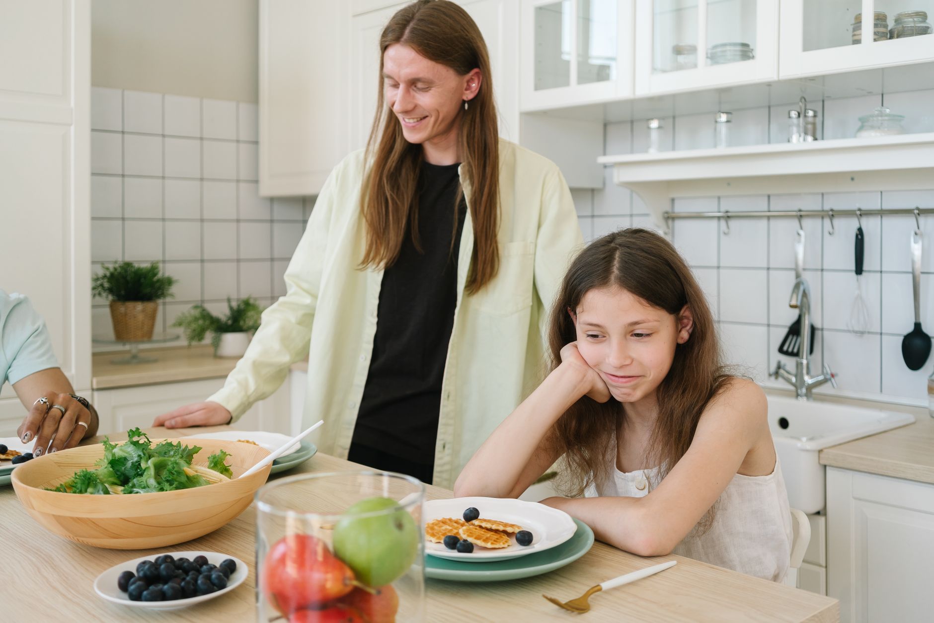 Adolescente sonriente con un plato de comida saludable y colorida sobre la mesa