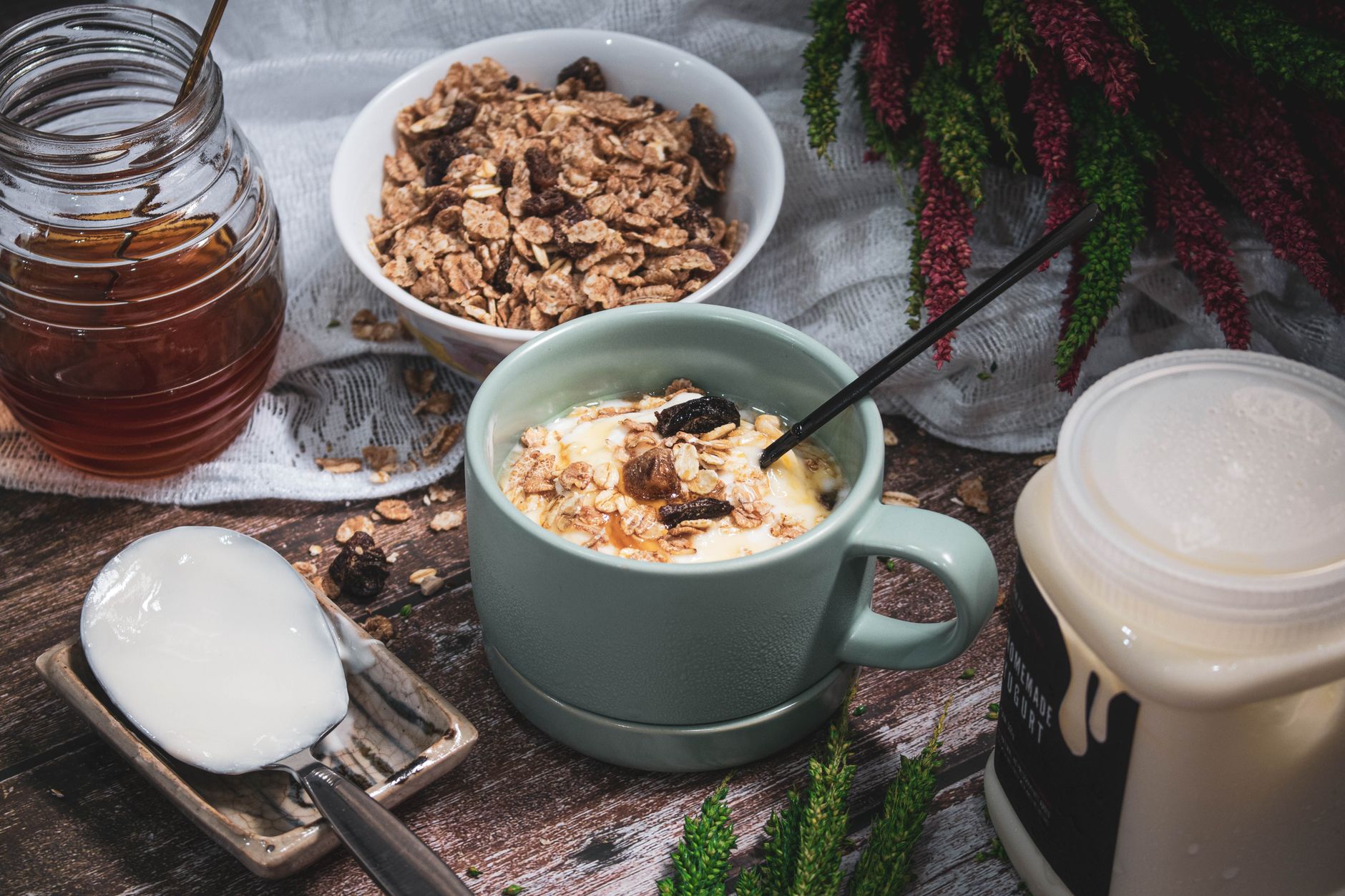 Un desayuno acogedor con cereal, miel y yogur sobre una mesa de madera rústica.