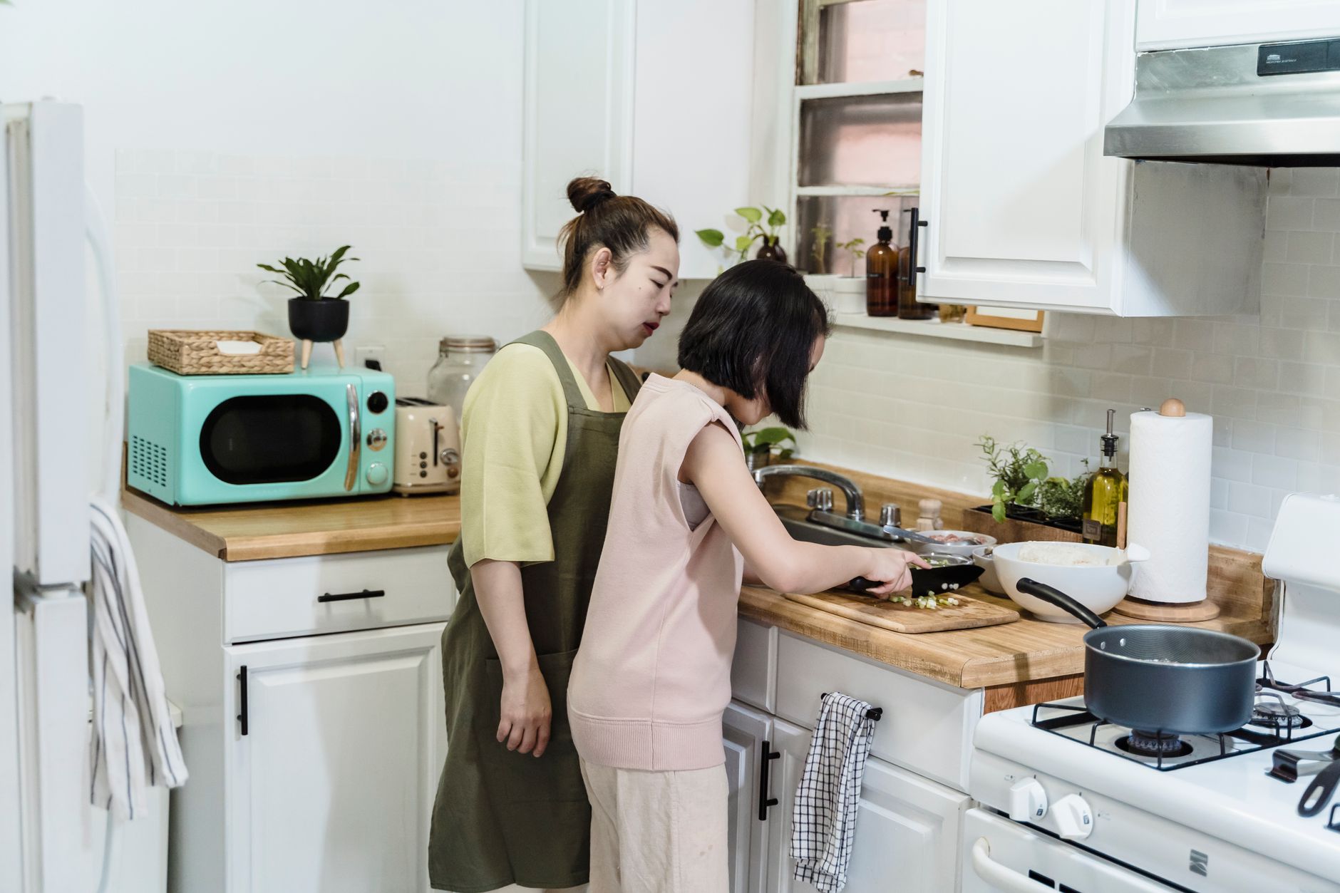 Madre e hija preparando verduras coloridas juntas en la cocina
