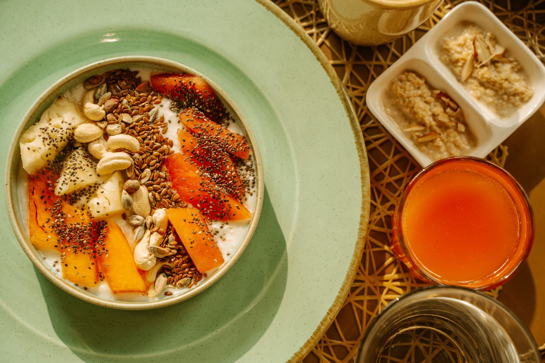 Desayuno saludable con bowl de avena, frutas, semillas de chía y tostada integral con aguacate sobre mesa de madera