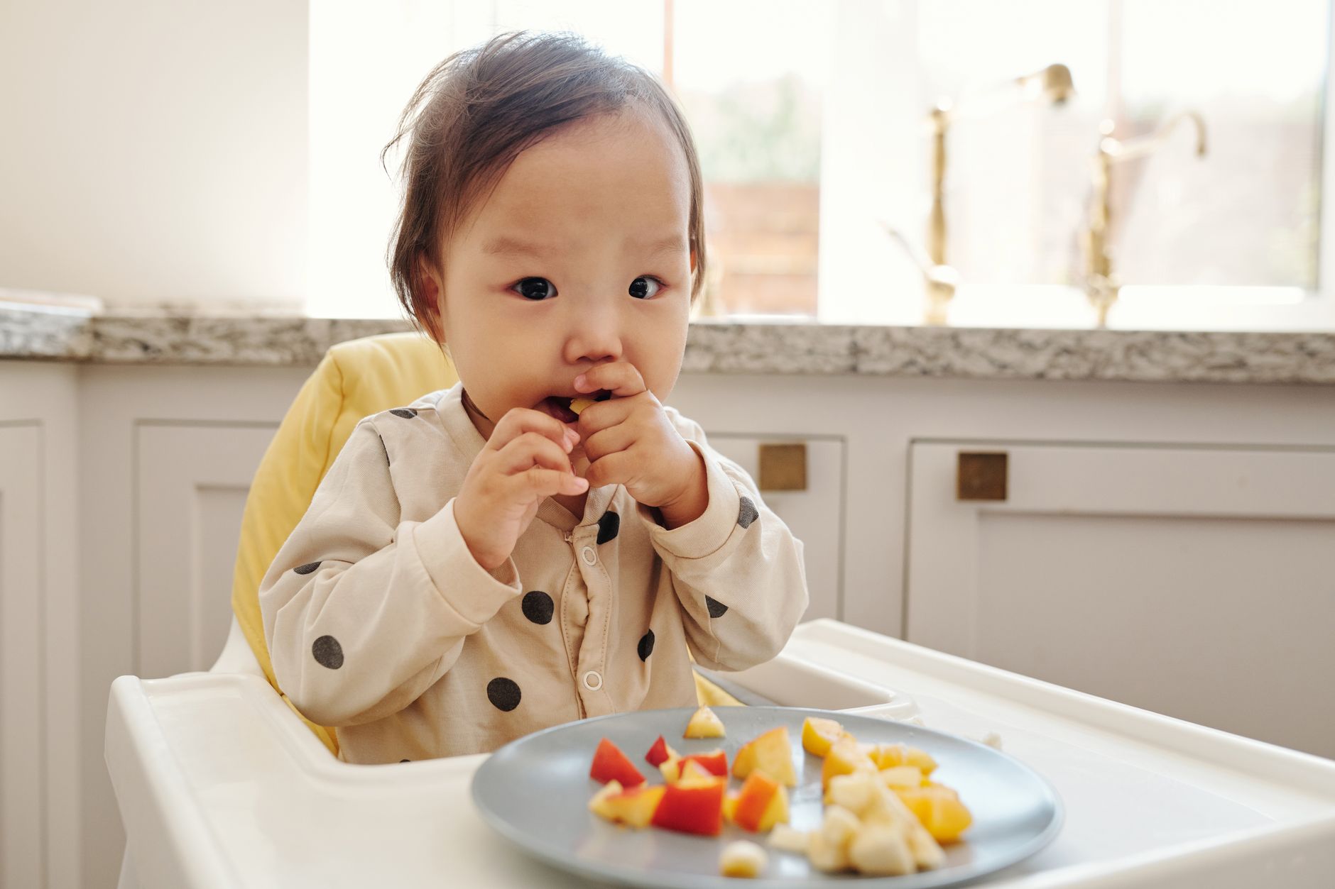Niña sonriente comiendo frutas y verduras coloridas en la mesa familiar