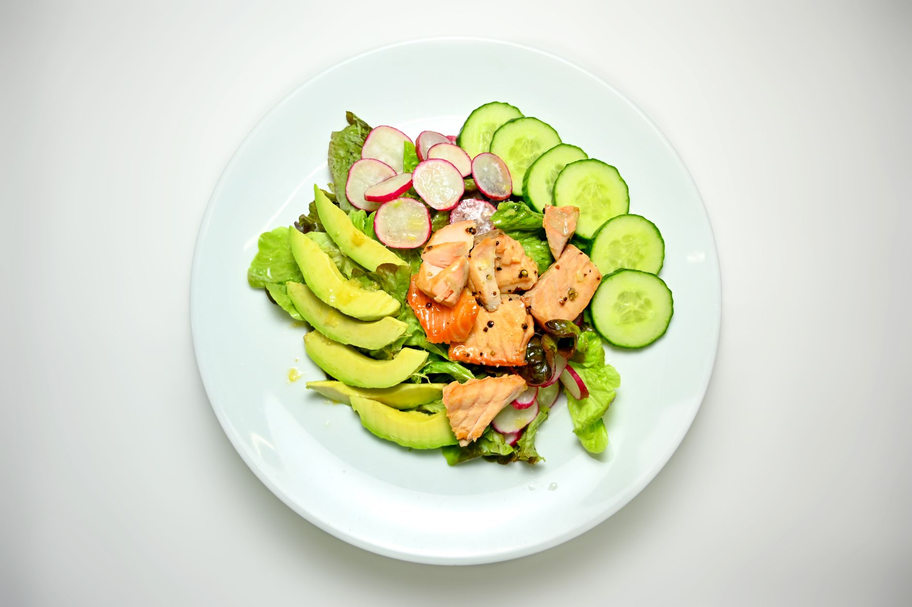 Plato saludable con lentejas, aguacate, salmón y verduras verdes para apoyar la salud del hígado
