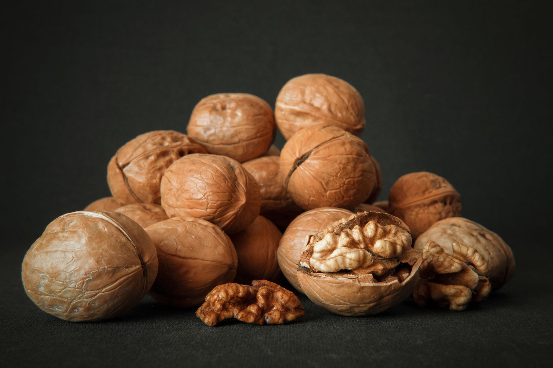 Alimentos ricos en magnesio como nueces, semillas y verduras de hoja verde sobre superficie clara