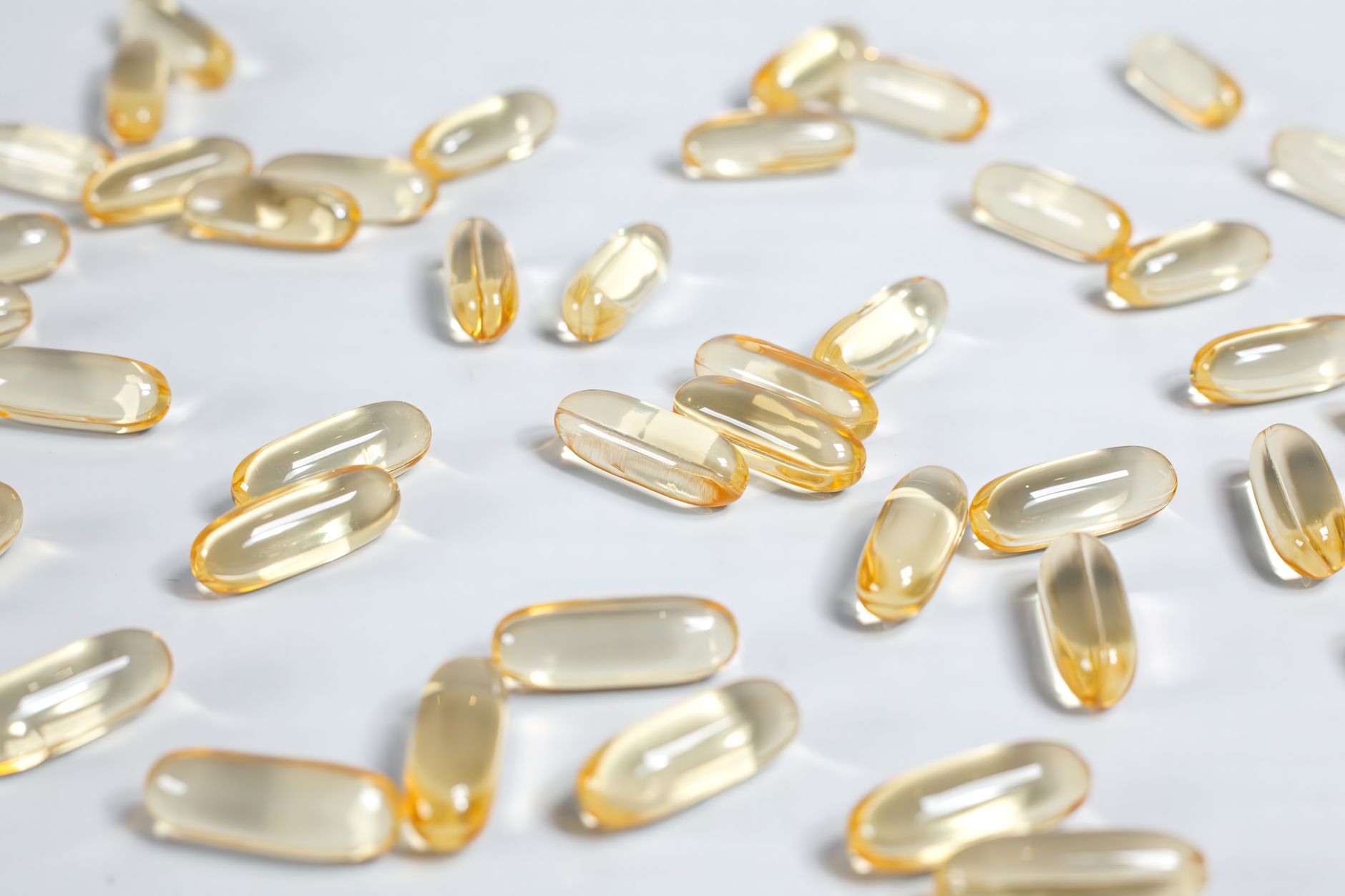 Cápsulas de aceite de pescado rico en omega-3 sobre superficie blanca, suplemento nutricional natural