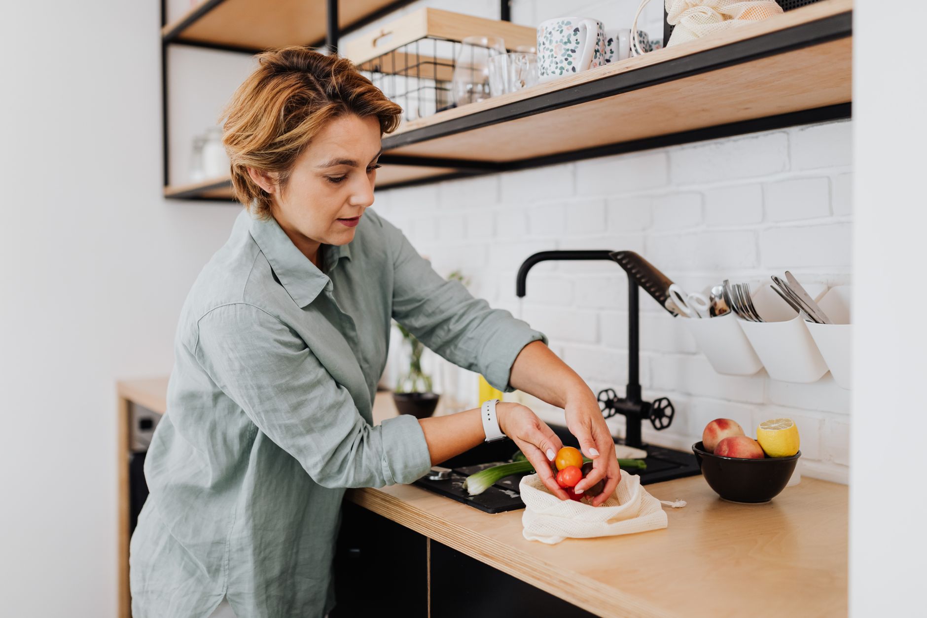 Plato saludable con proteína, quinoa y verduras coloridas sobre mesa de cocina iluminada con luz natural.