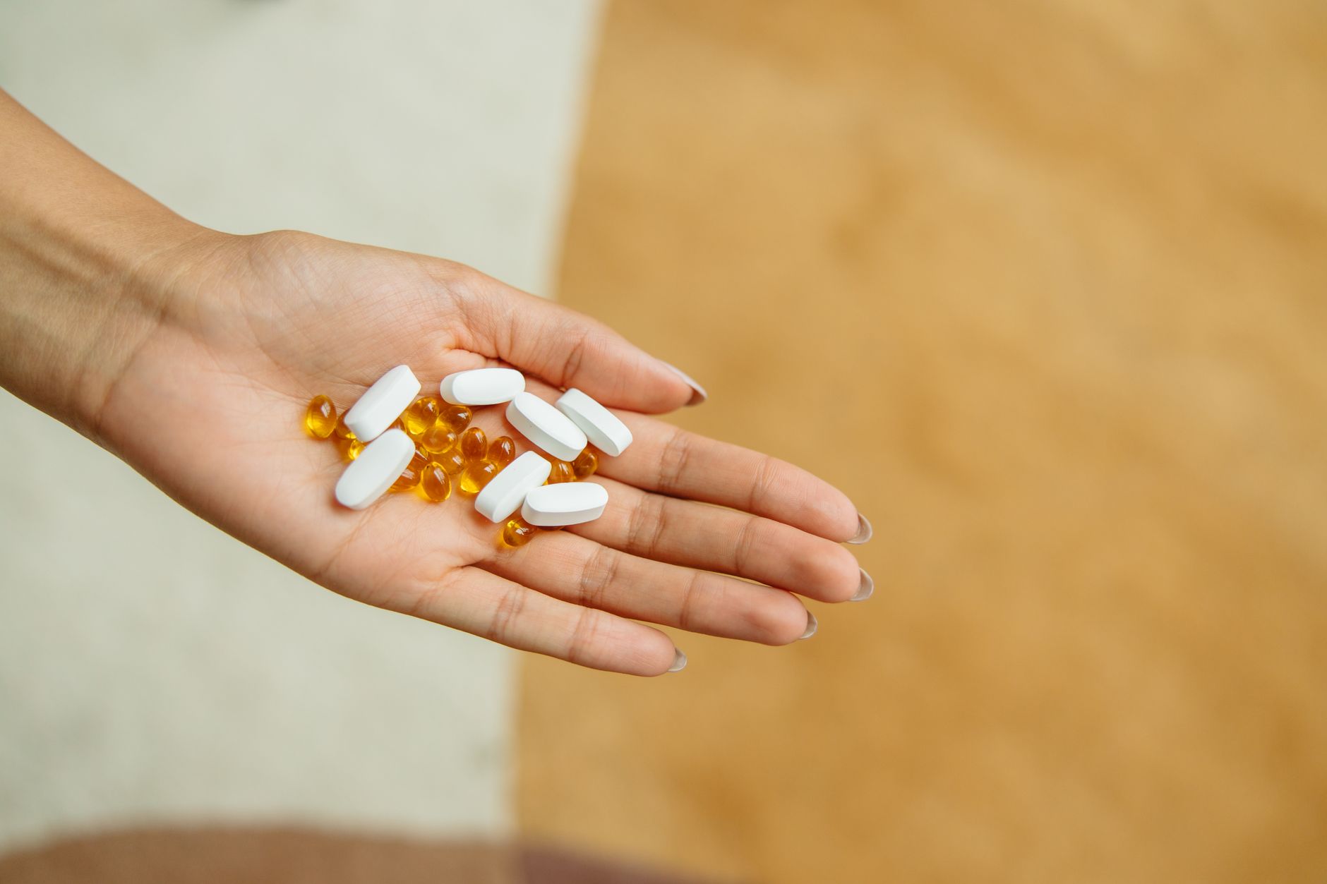 Mujer sosteniendo suplementos vitamínicos junto a un vaso de agua en un entorno de bienestar femenino